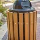 Outdoor trash can on a brick sidewalk.