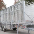 A large metal trailer with a ramp and side rails.