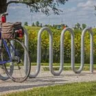 Bicycle parked in a bike rack near a field and sign.