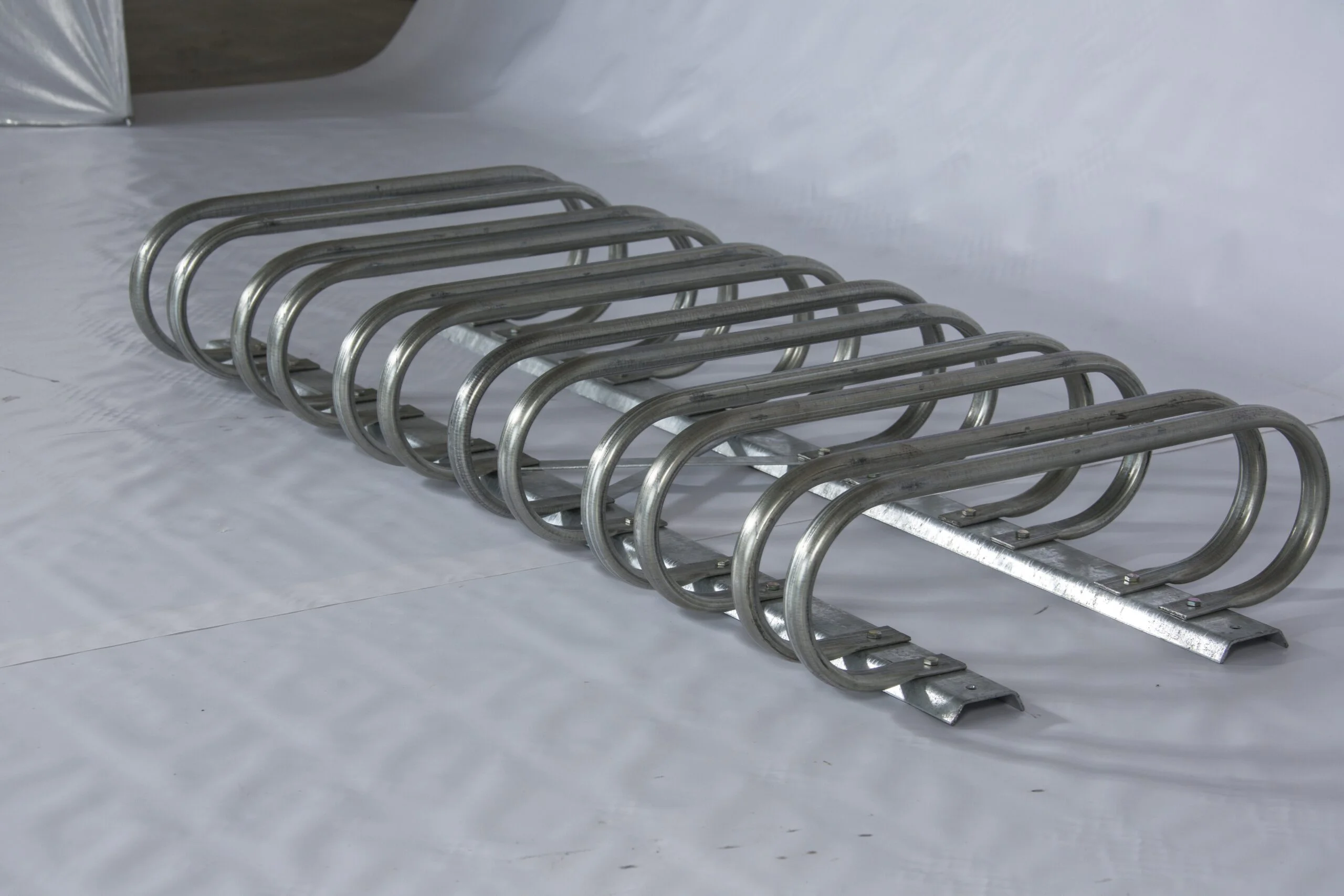 Stainless steel bike rack on a white surface.