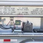 Folding bleacher control panel with instructions and warning labels.