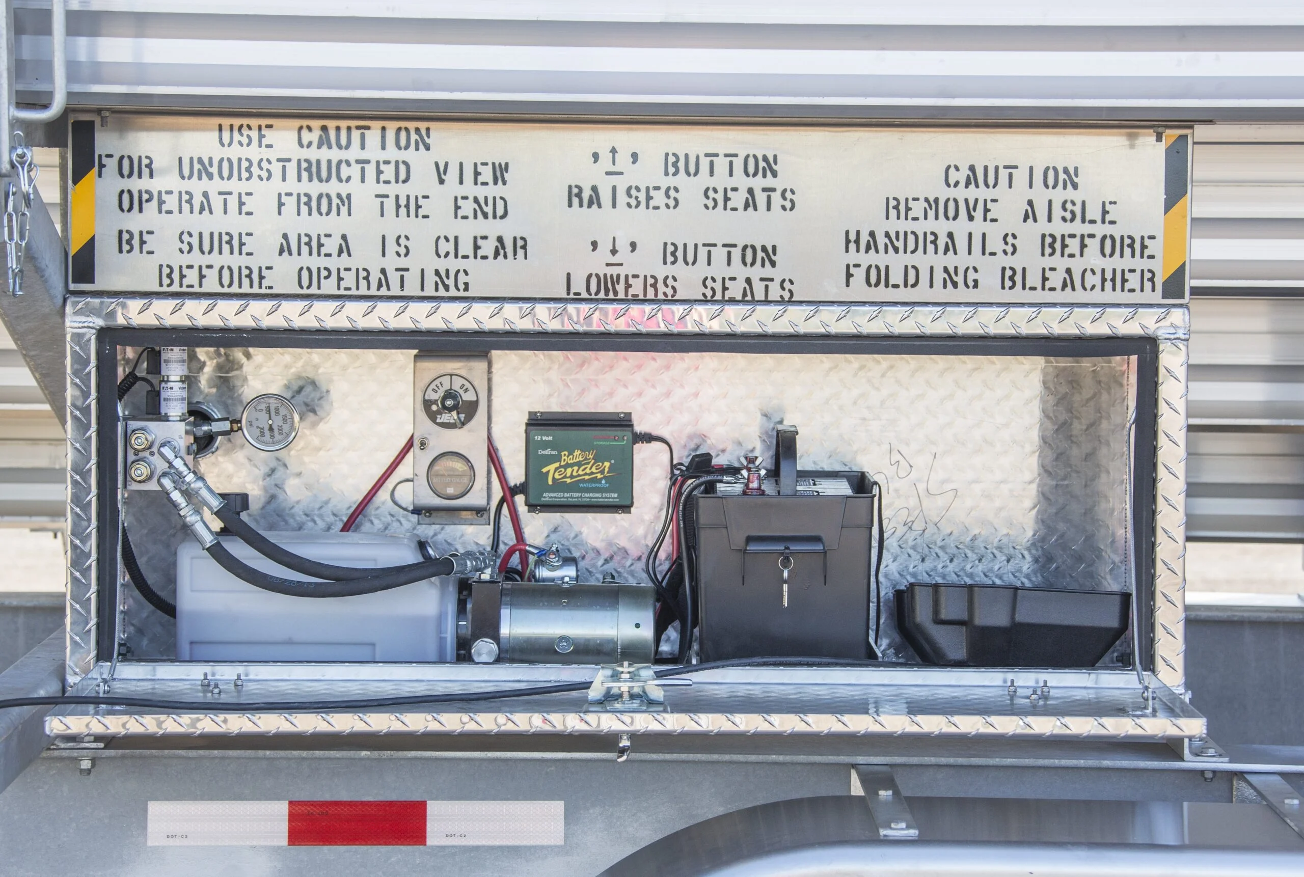 Folding bleacher control panel with instructions and warning labels.