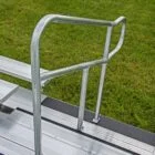 Metal ladder with handrail on grassy background.
