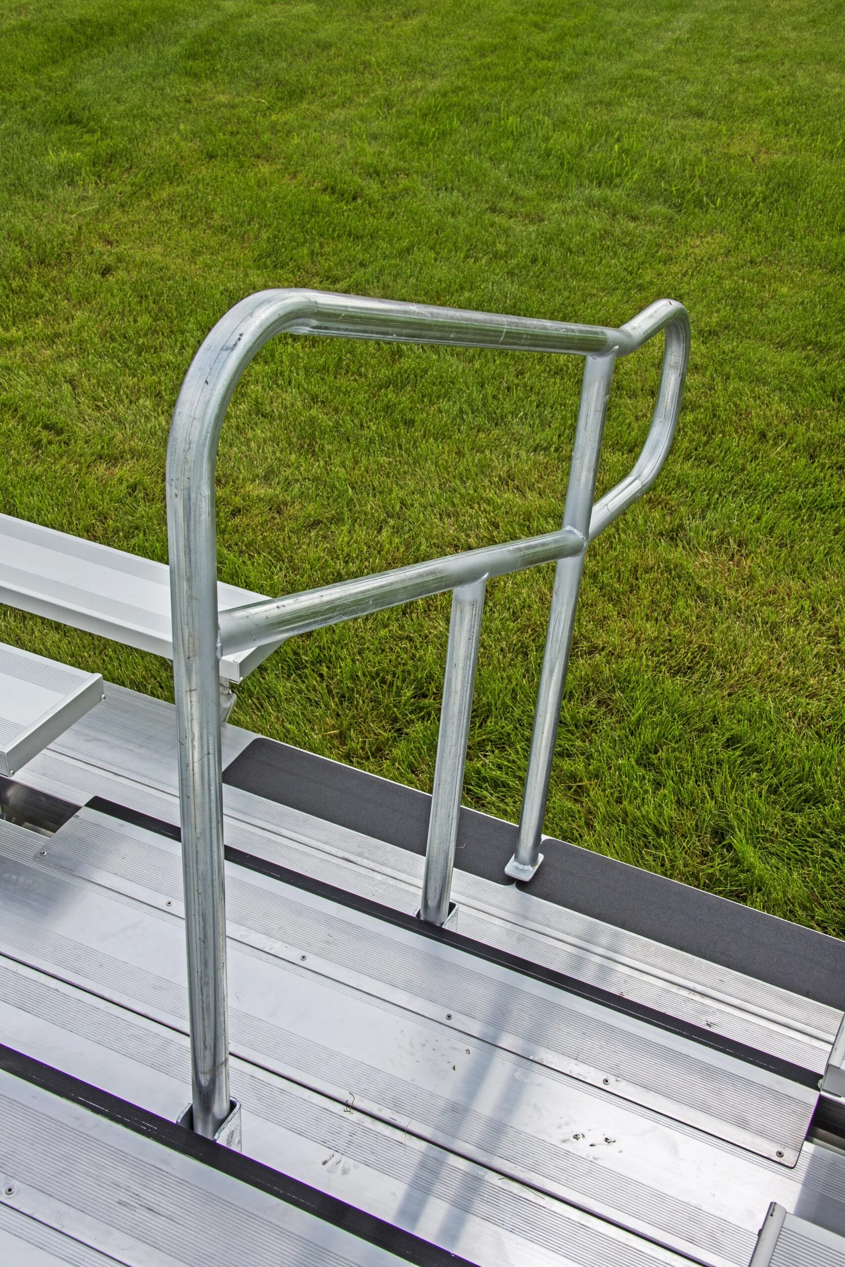 Metal ladder with handrail on grassy background.