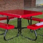 Red picnic table and benches on grass.