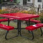Red picnic table with black legs and benches in a garden setting.