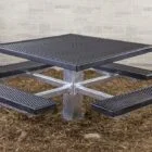Square metal picnic table with textured surfaces and a central pedestal.