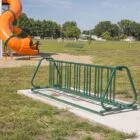 Green bike rack in a park setting.