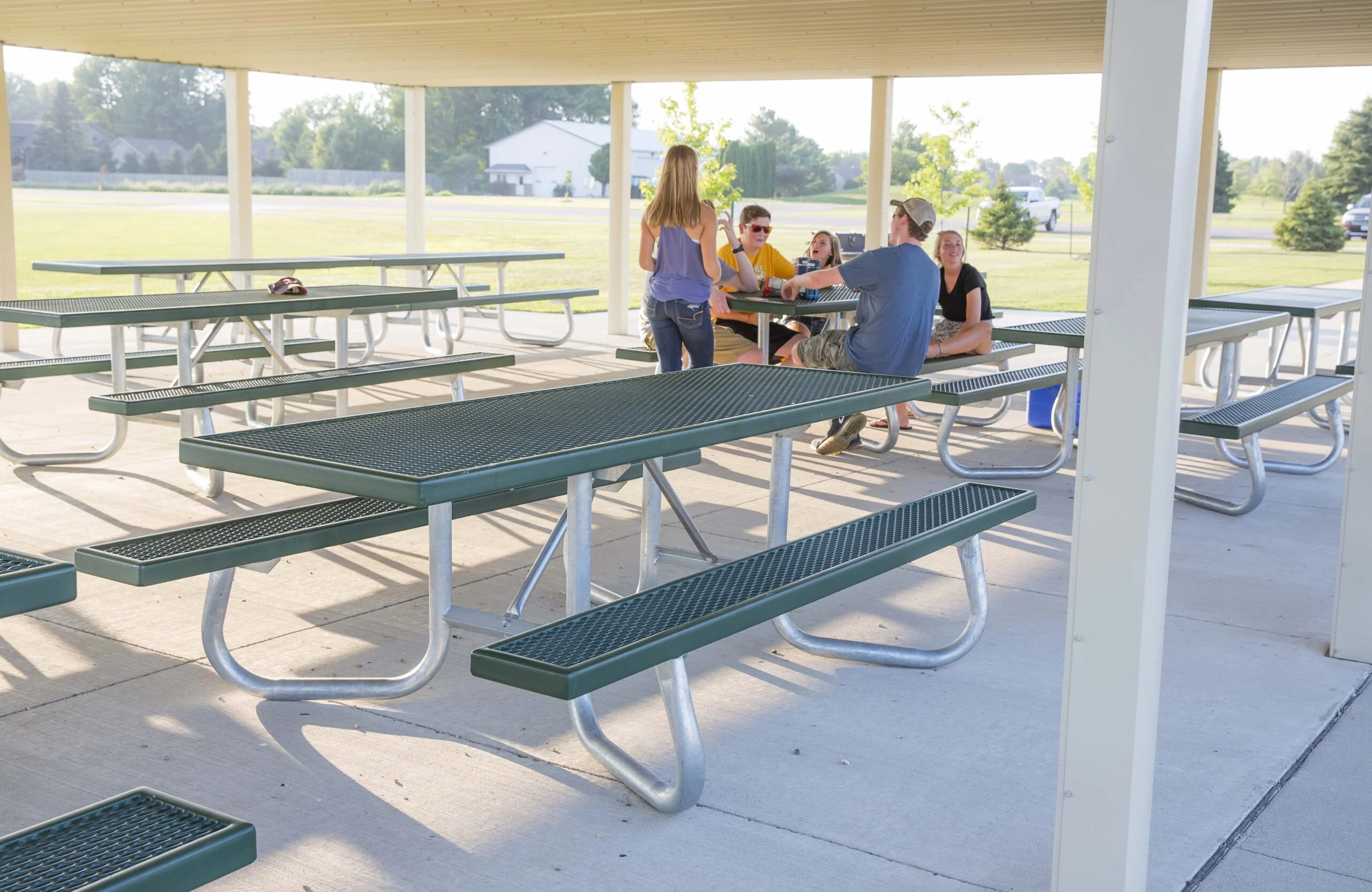 Outdoor picnic tables and benches in a covered area.