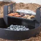 Outdoor grill cooking hot dogs and burgers over charcoal.