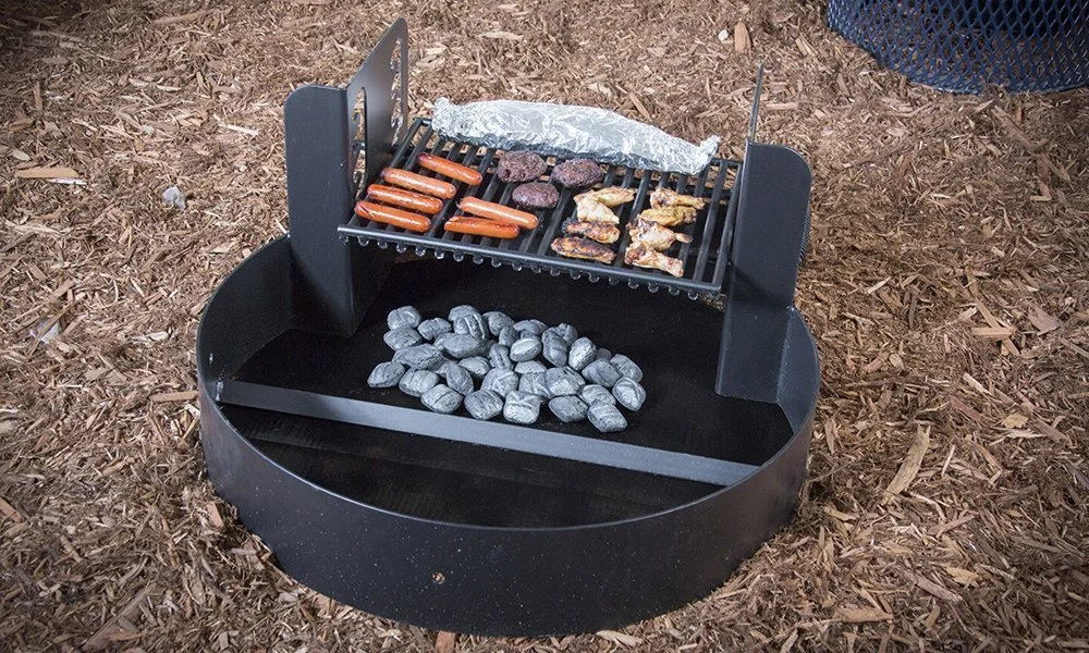 Portable grill with food cooking on top and rocks in bottom.