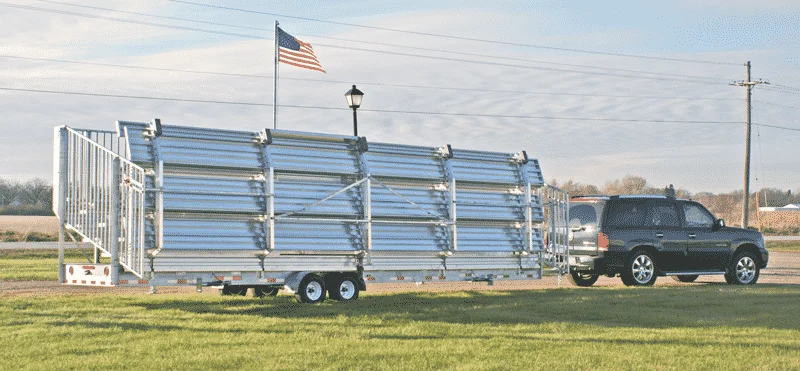 Trailer with metal panels and American flag on a rural road.