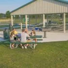 People sitting at a picnic table in an outdoor pavilion.