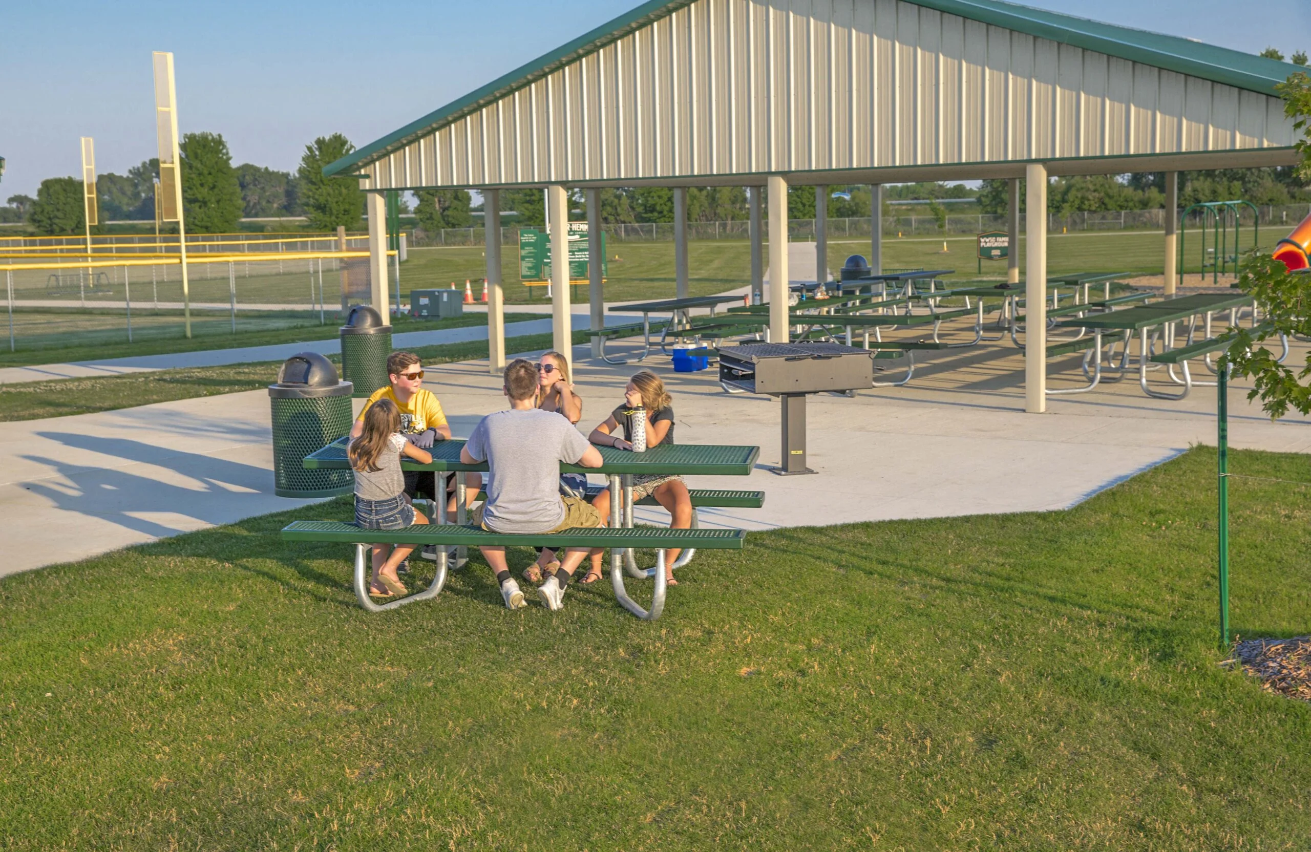 People sitting at a picnic table in an outdoor pavilion.