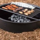 Black portable grill with charcoal and food cooking on it.