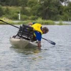 Man paddling kayak in calm water.