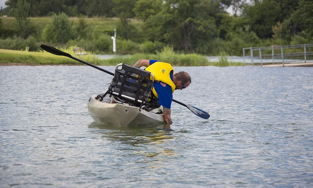 Man paddling kayak in calm water.