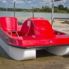 Red and white pedal boat on a dock.
