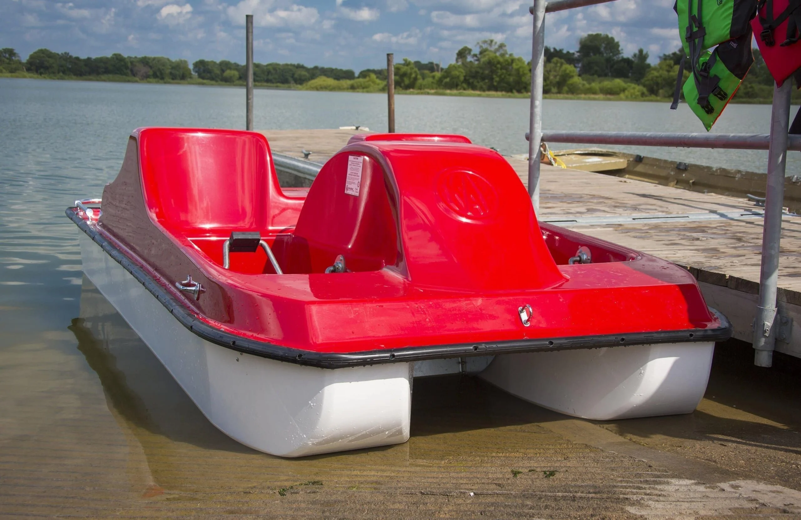 Red and white pedal boat on a dock.