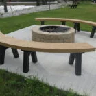 Outdoor curved bench and fire pit in a park setting.
