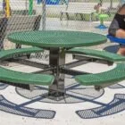 Outdoor seating area with green benches and a round table.