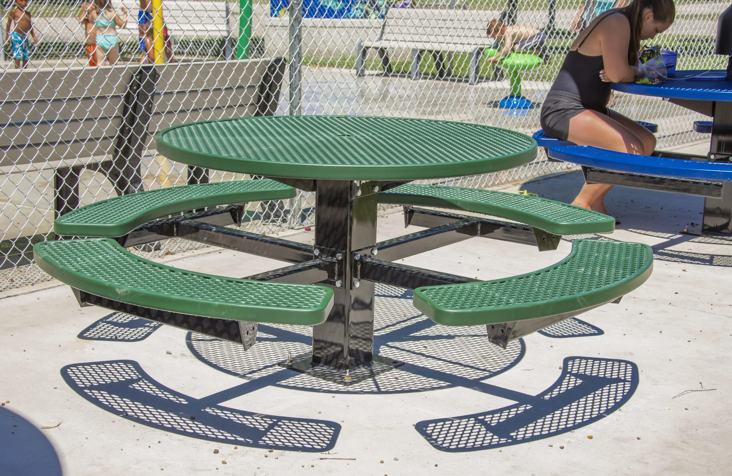 Outdoor seating area with green benches and a round table.