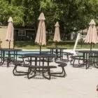 Poolside tables and umbrellas by a swimming pool.