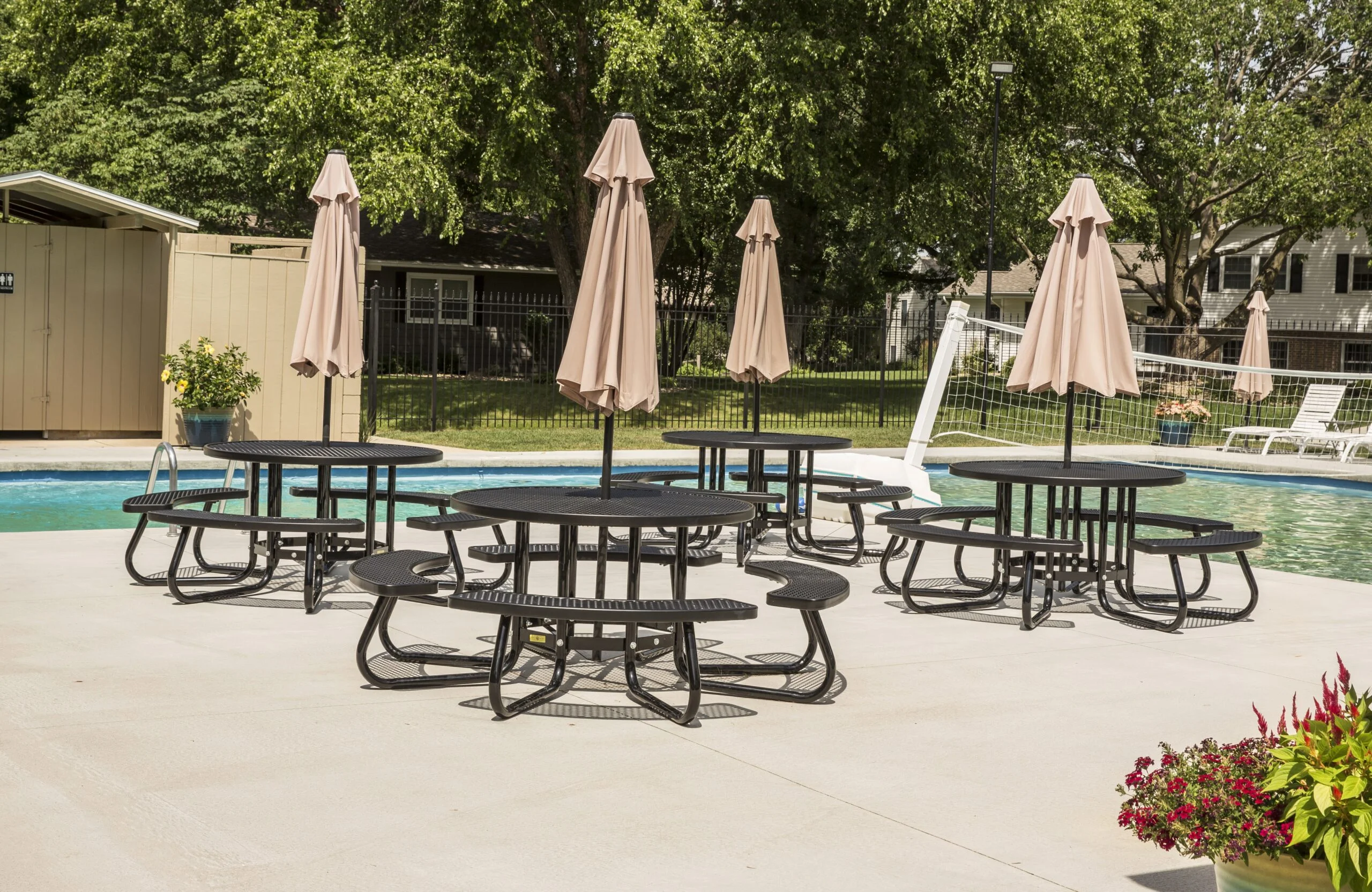 Poolside tables and umbrellas by a swimming pool.
