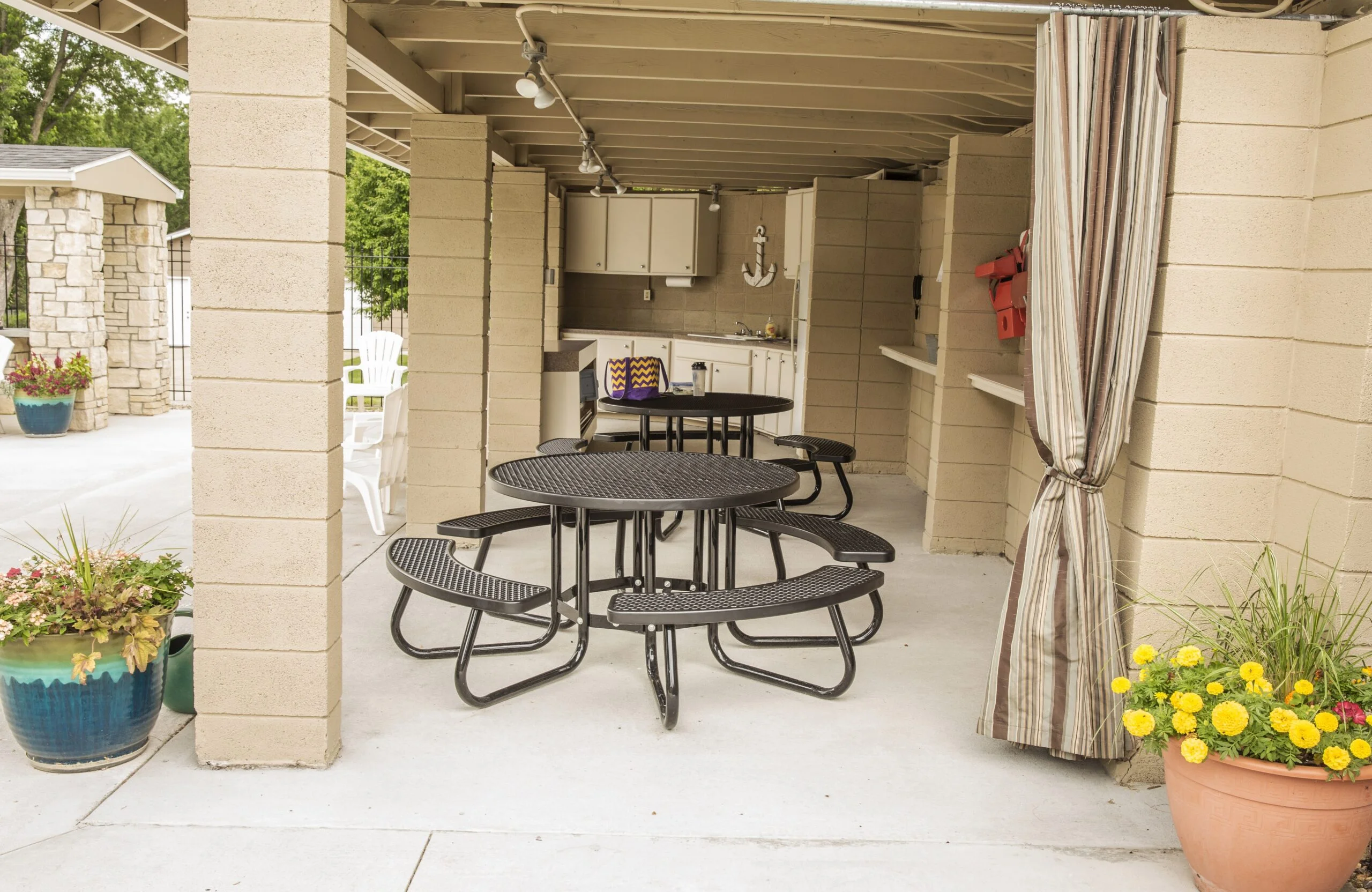 Outdoor patio area with picnic tables and potted plants.