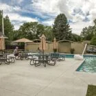 Poolside picnic area with tables and umbrellas near a swimming pool.