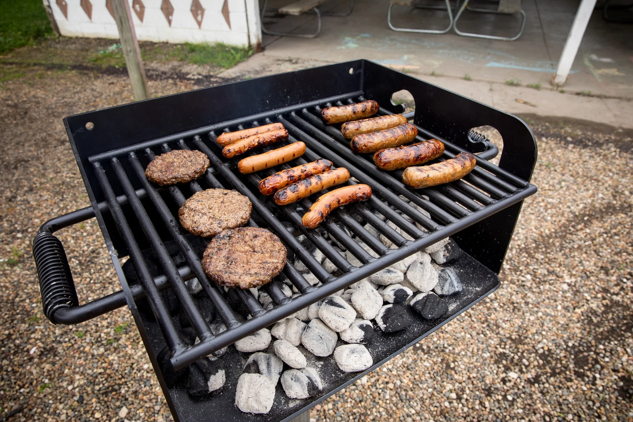 Charcoal grill cooking burgers and sausages.