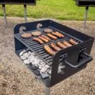 Outdoor grill cooking burgers and sausages on a stone-lined base.
