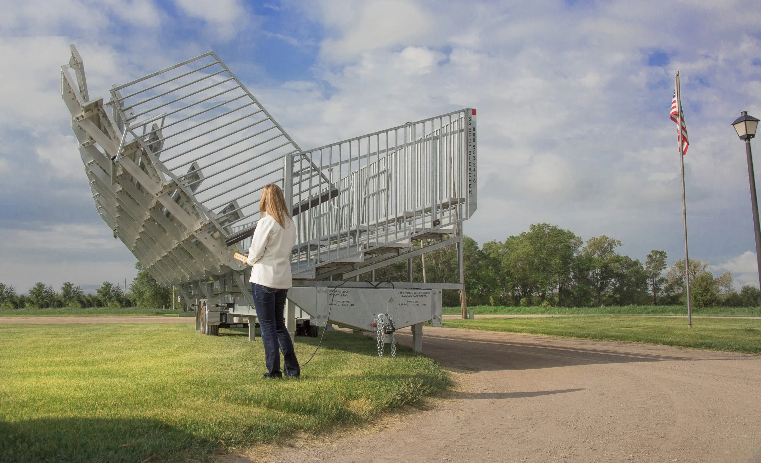 Woman standing next to a large metal structure on grass.
