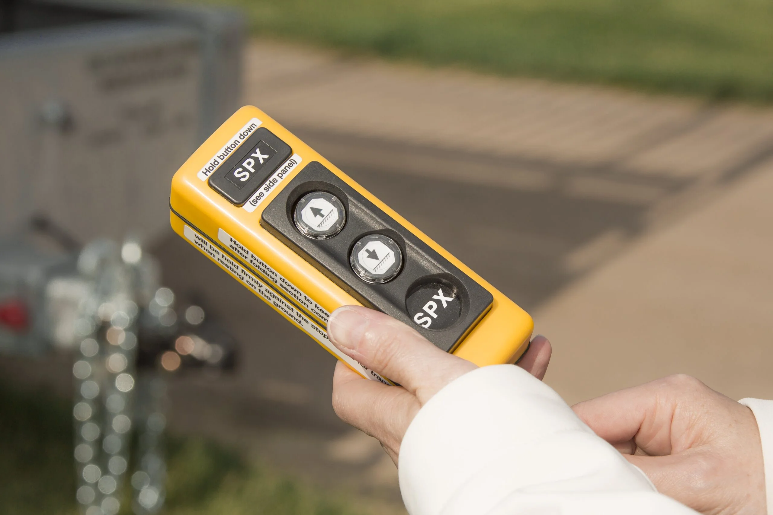 Hand holding a yellow device labeled SPX.