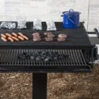 Outdoor grill setup with hot dogs, burgers, and charcoal.