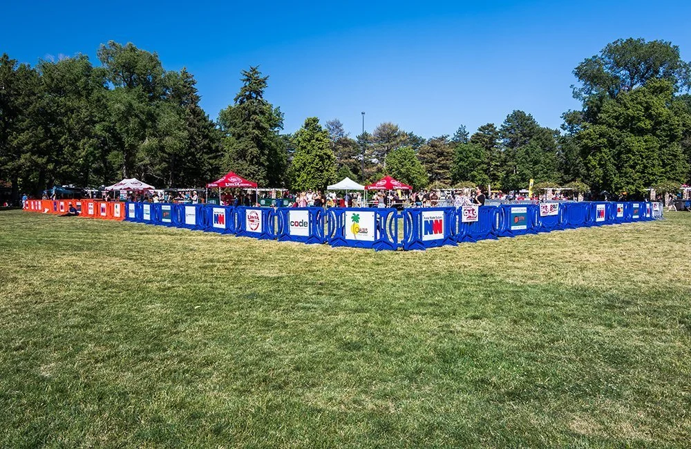 Outdoor event setup with tents and barriers in a park.