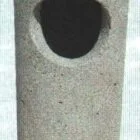 Concrete trash can with a round opening.