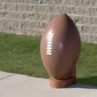 Football on grass against brick wall.