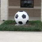 Large soccer ball sculpture in front of a building.