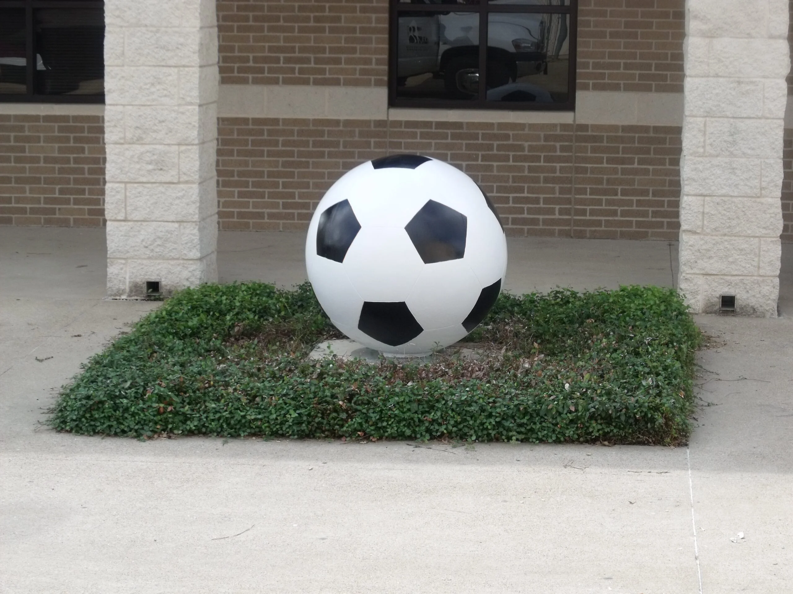 Large soccer ball sculpture in front of a building.
