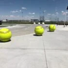 Yellow softball balls on a concrete surface.