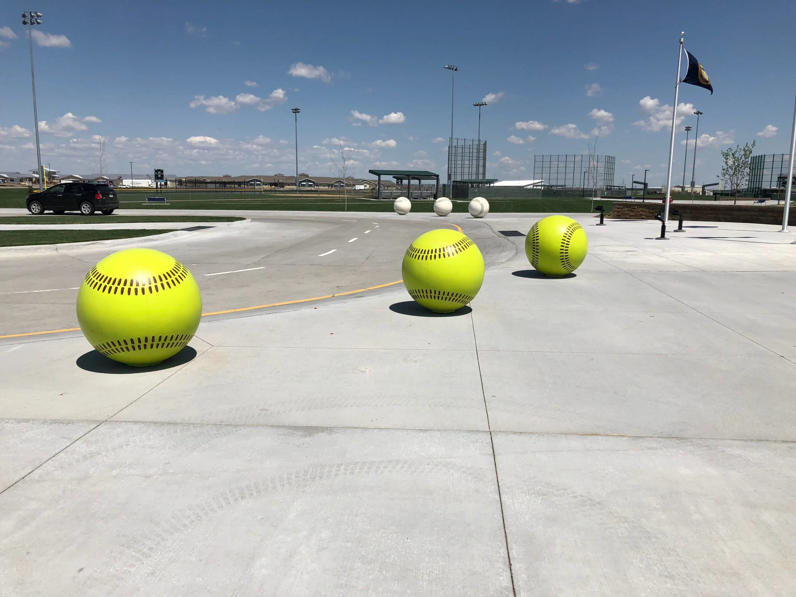 Yellow softball balls on a concrete surface.