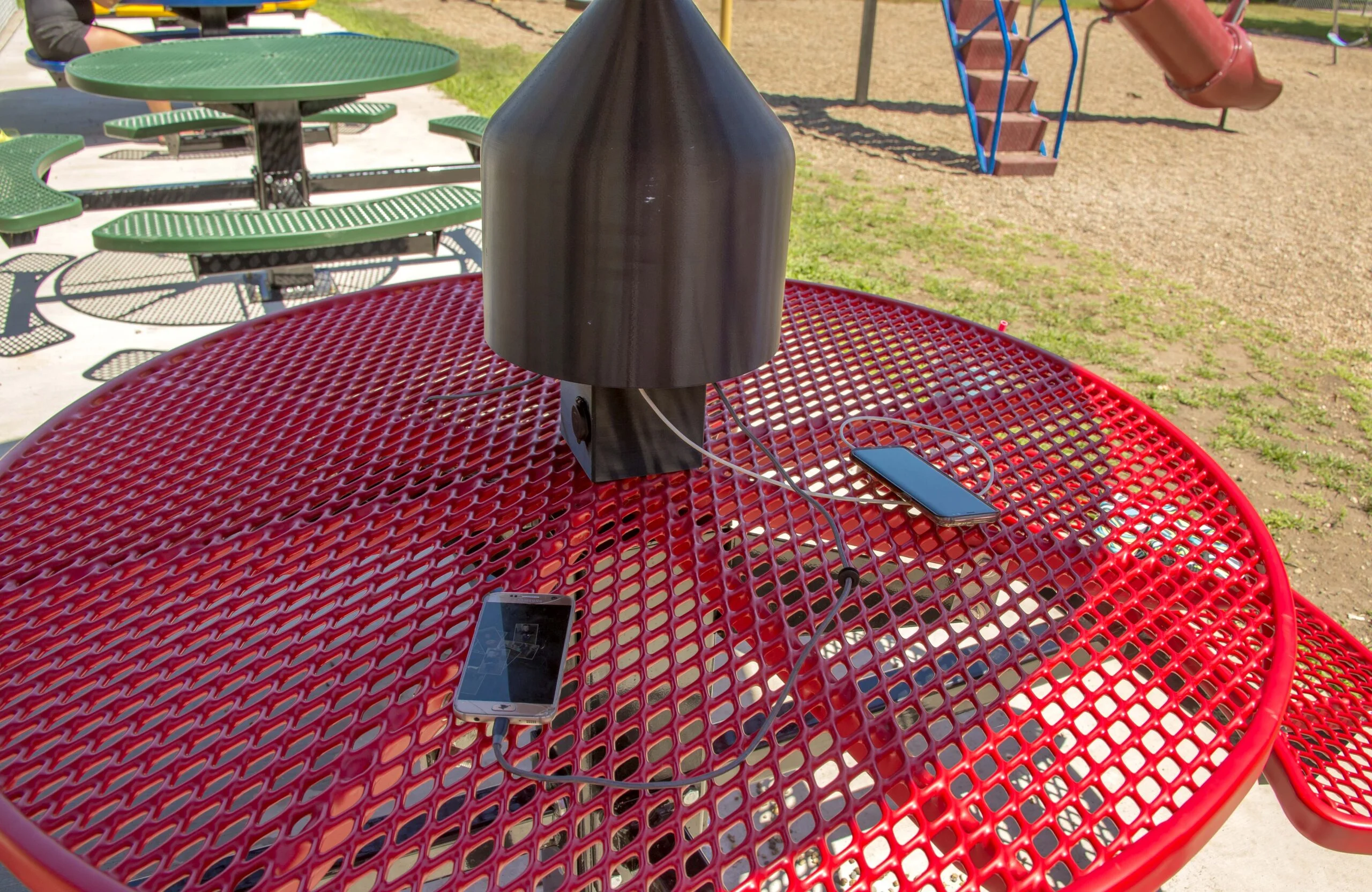 Outdoor charging station on a red table in a playground.