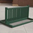 Green metal bench on a sidewalk.