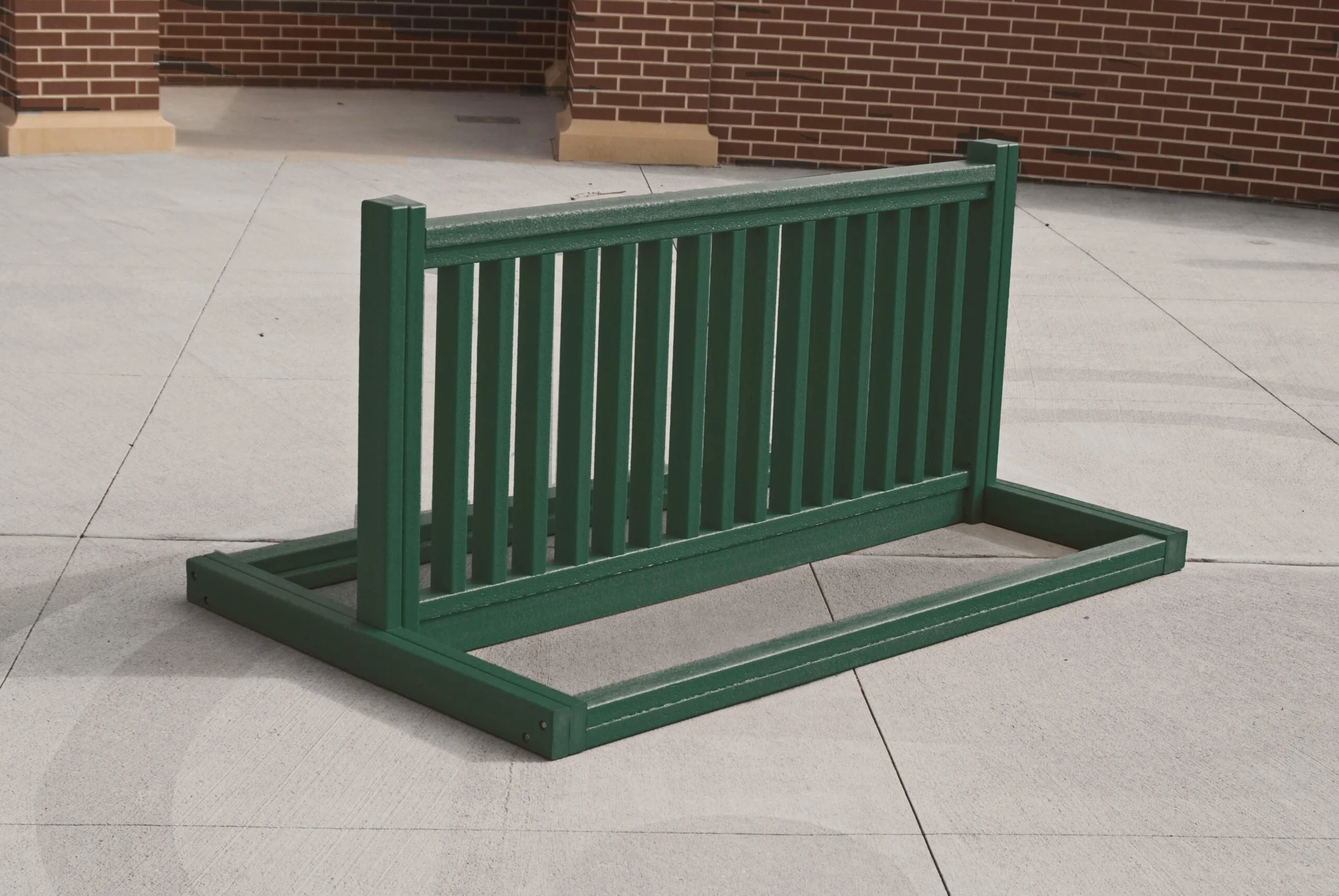 Green metal bench on a sidewalk.