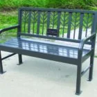 Metal park bench with decorative backrest and armrests.