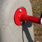 Red metal pole attached to a concrete post.