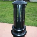 Black cylindrical trash can on a sidewalk.