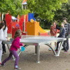 Children playing ping pong in a playground.