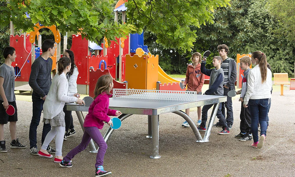 Children playing ping pong in a playground.